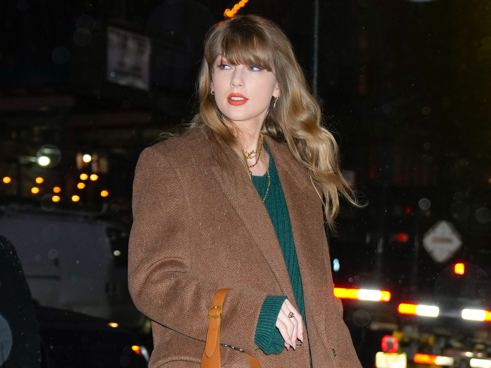 Taylor Swift's green jumper dress and brown coat combo screams Evermore to me